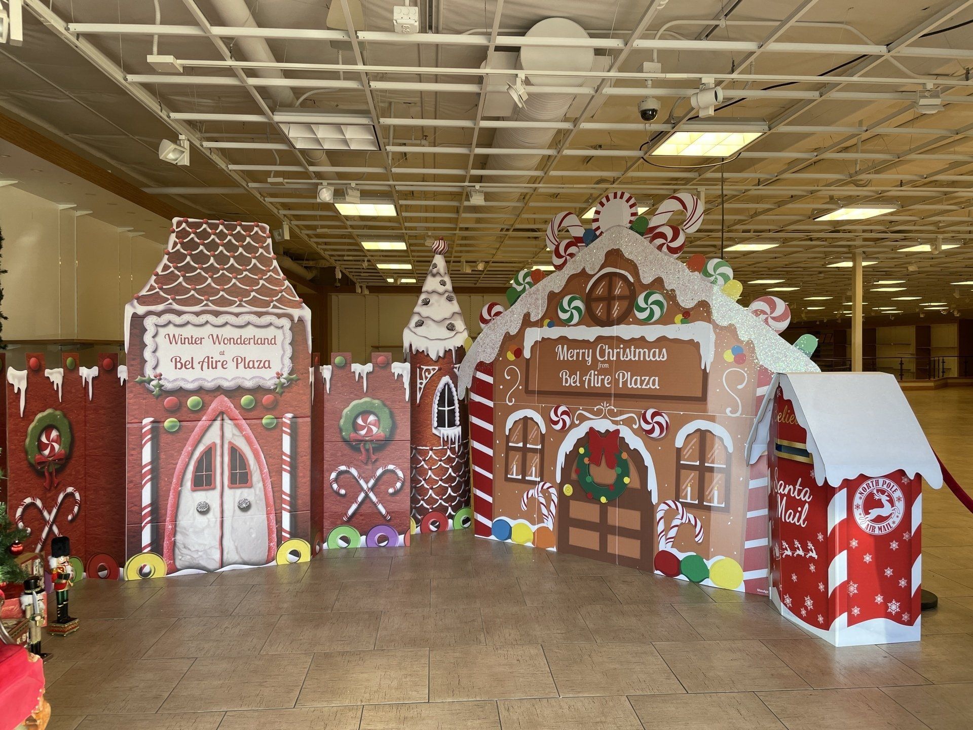 A large gingerbread house is sitting in the middle of an empty room.