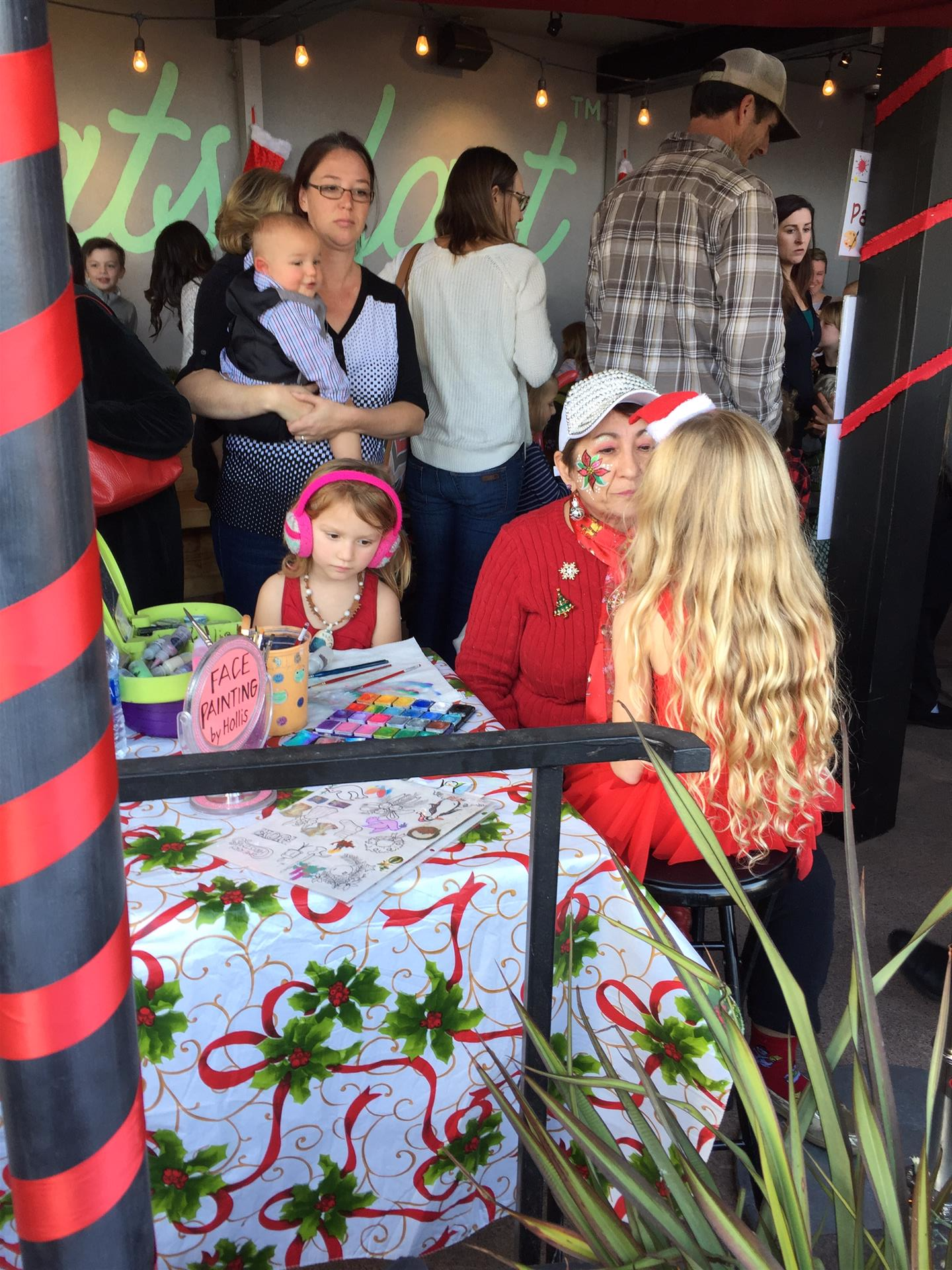 A group of people are gathered around a table with a candy cane table cloth
