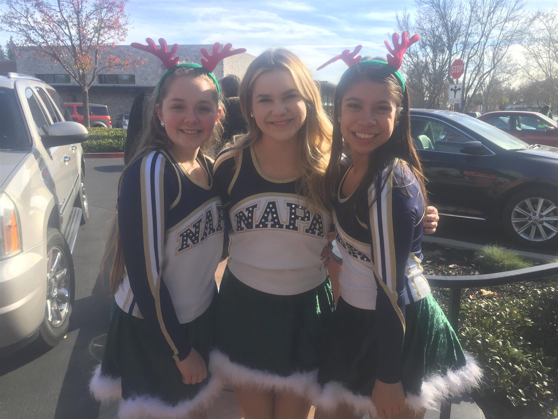 Three cheerleaders wearing santa hats are posing for a picture
