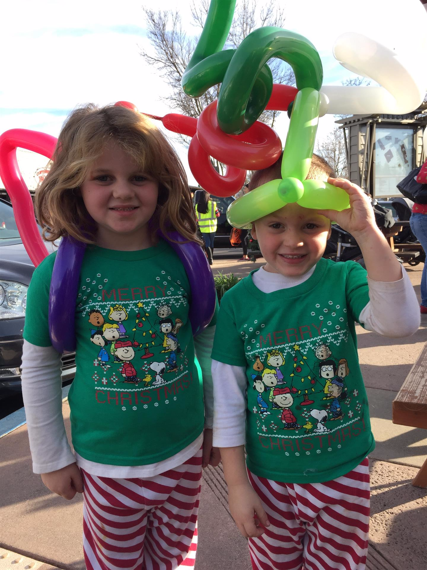 A boy and a girl are standing next to each other with balloons on their heads.