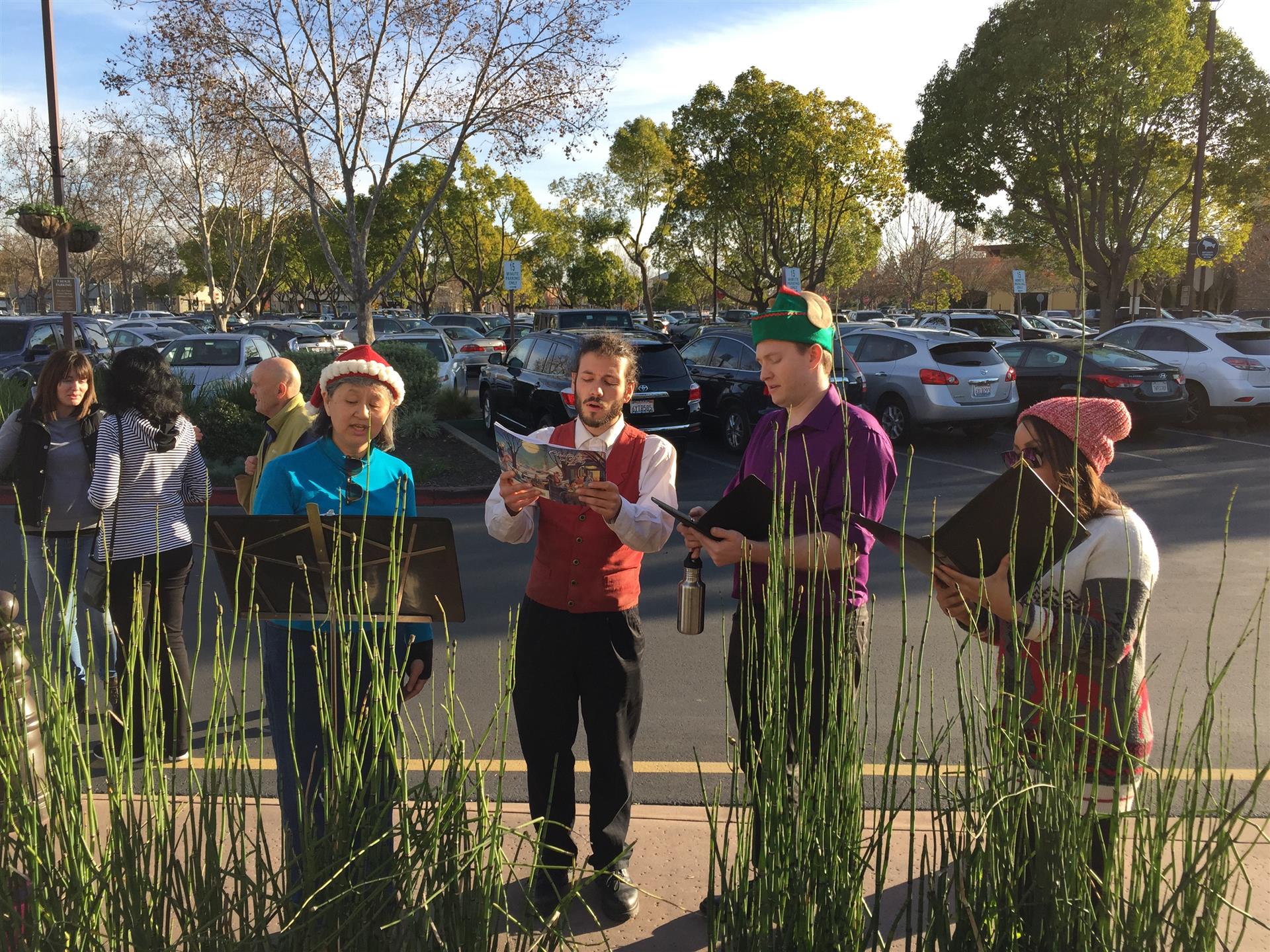 A group of people are singing christmas carols in a parking lot.