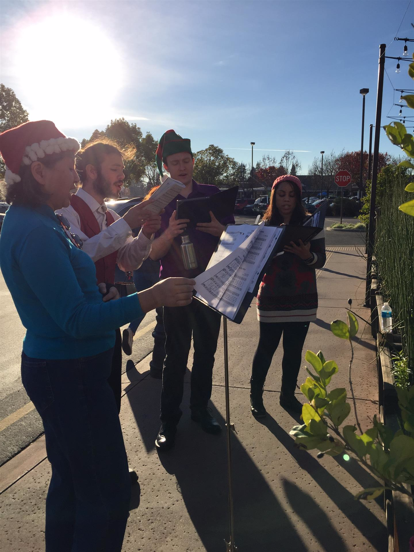 A group of people are singing christmas carols on a sidewalk.