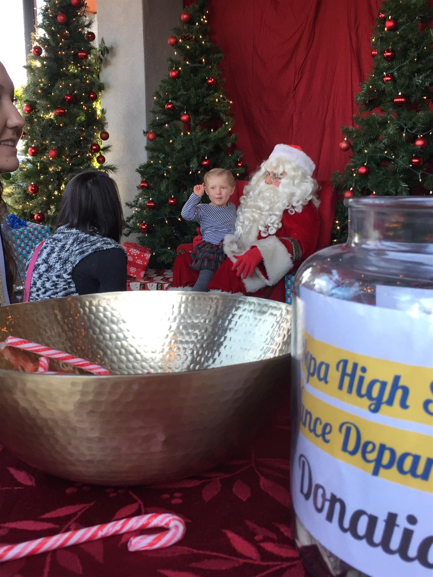 A child sits on santa 's lap next to a donation jar