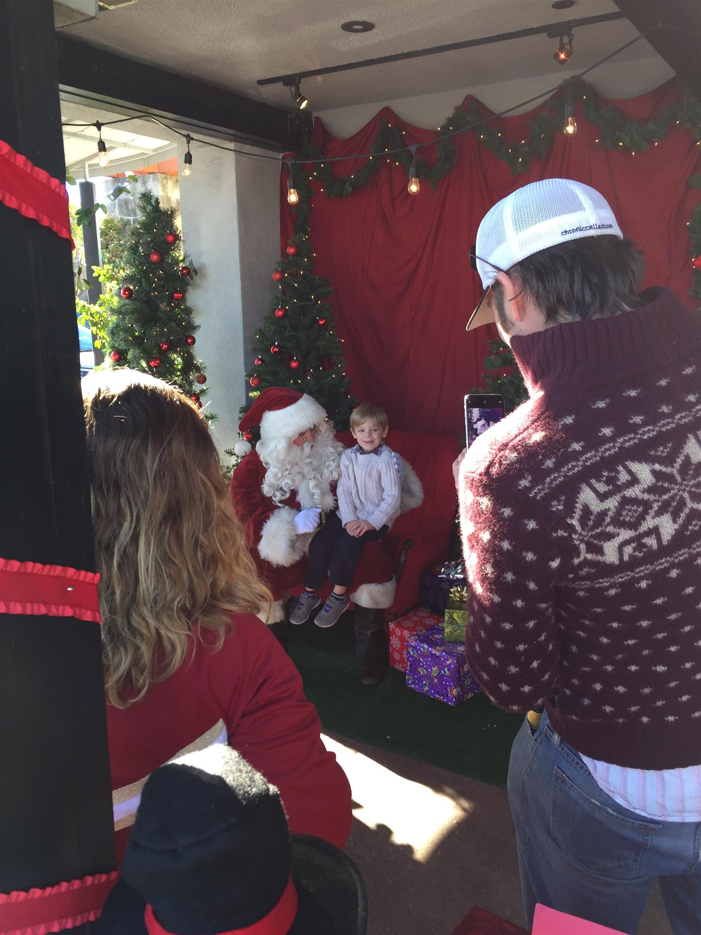 A man is taking a picture of santa claus and a child