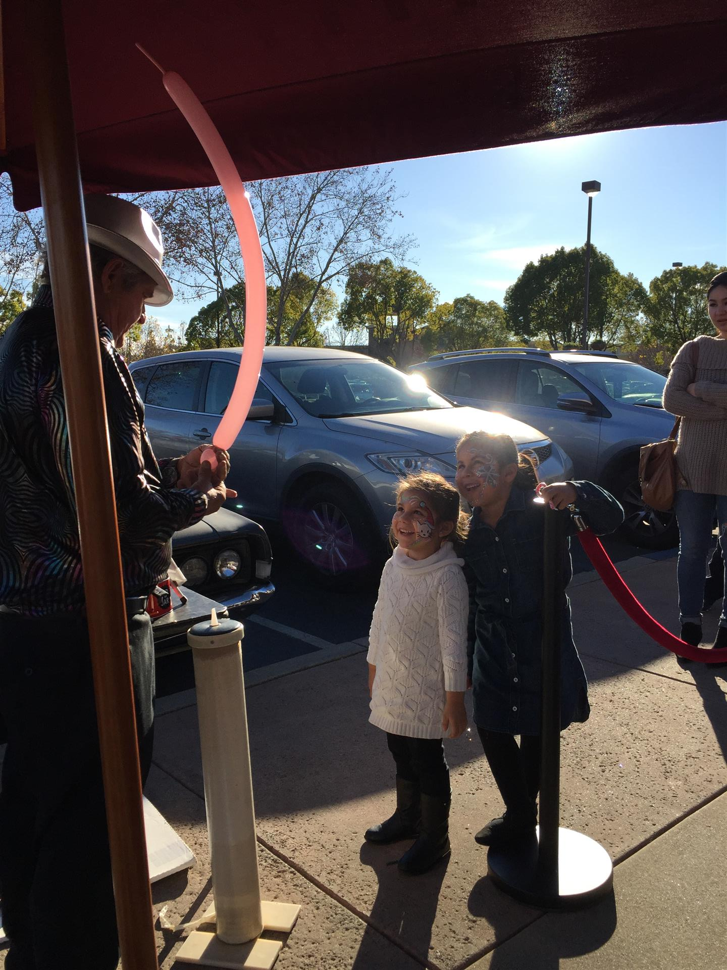 A little girl is standing next to a man holding a red balloon