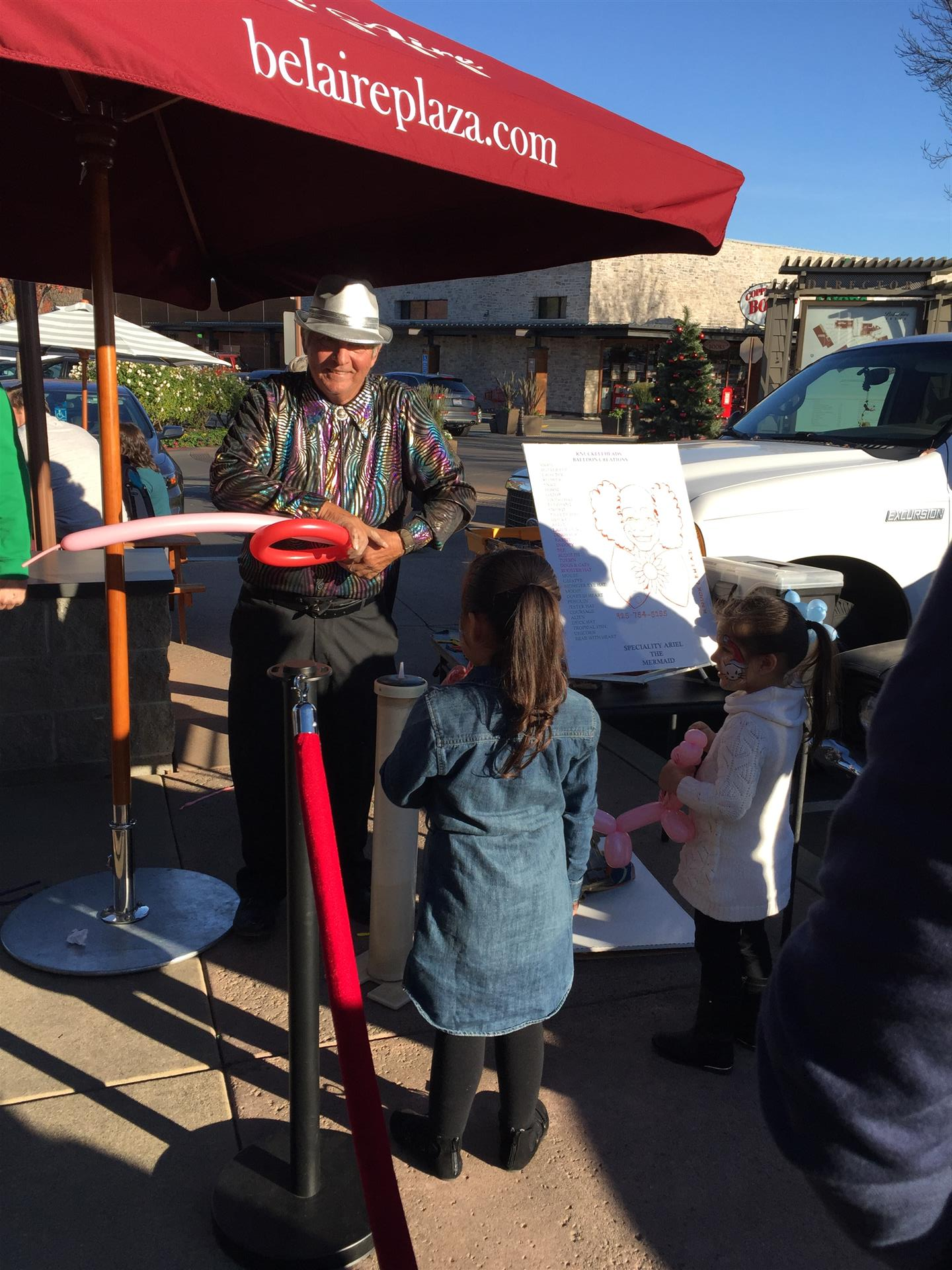 A man is sitting under an umbrella that says belairplaza.com