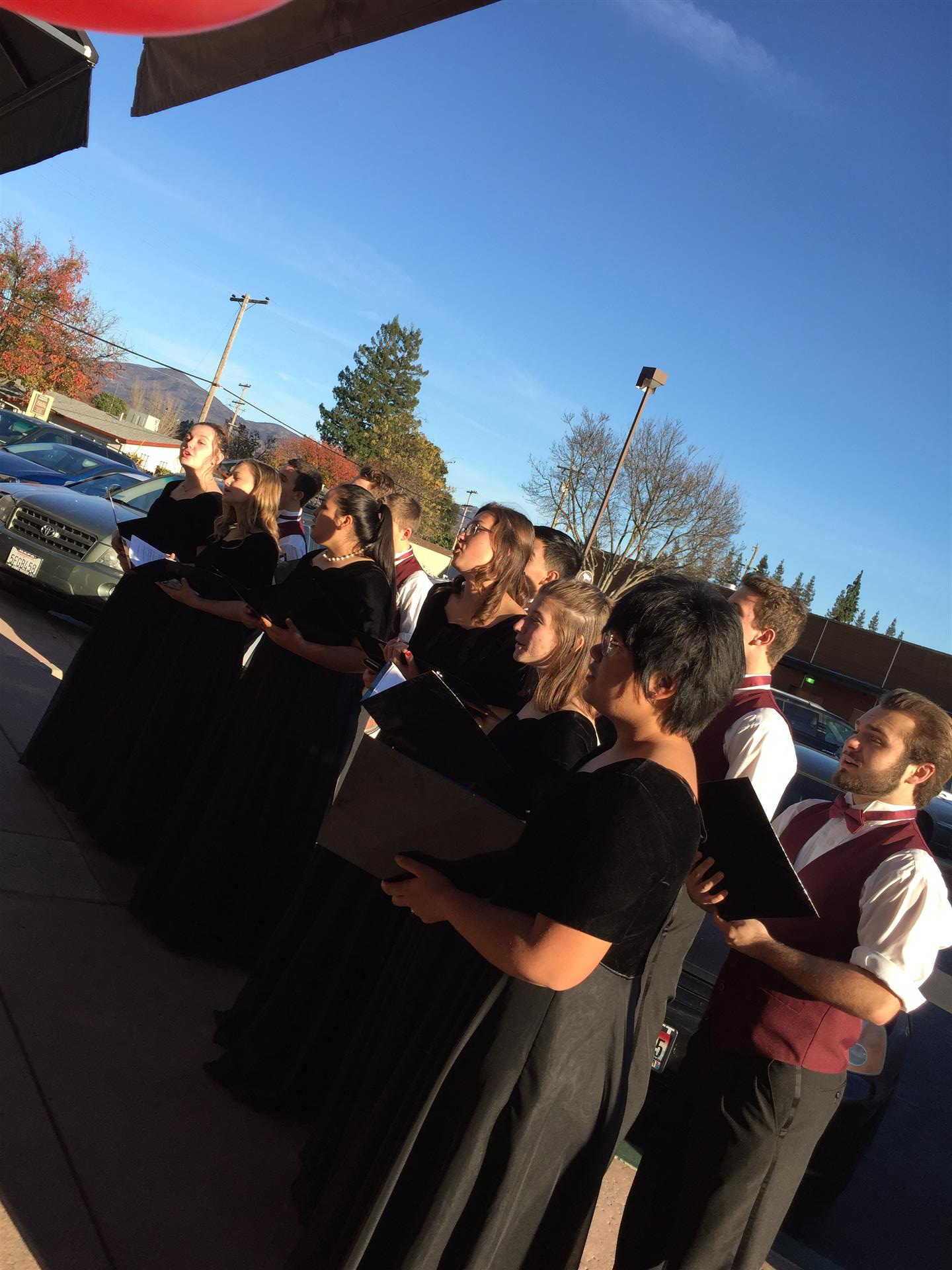 A group of people are singing in a choir outside.