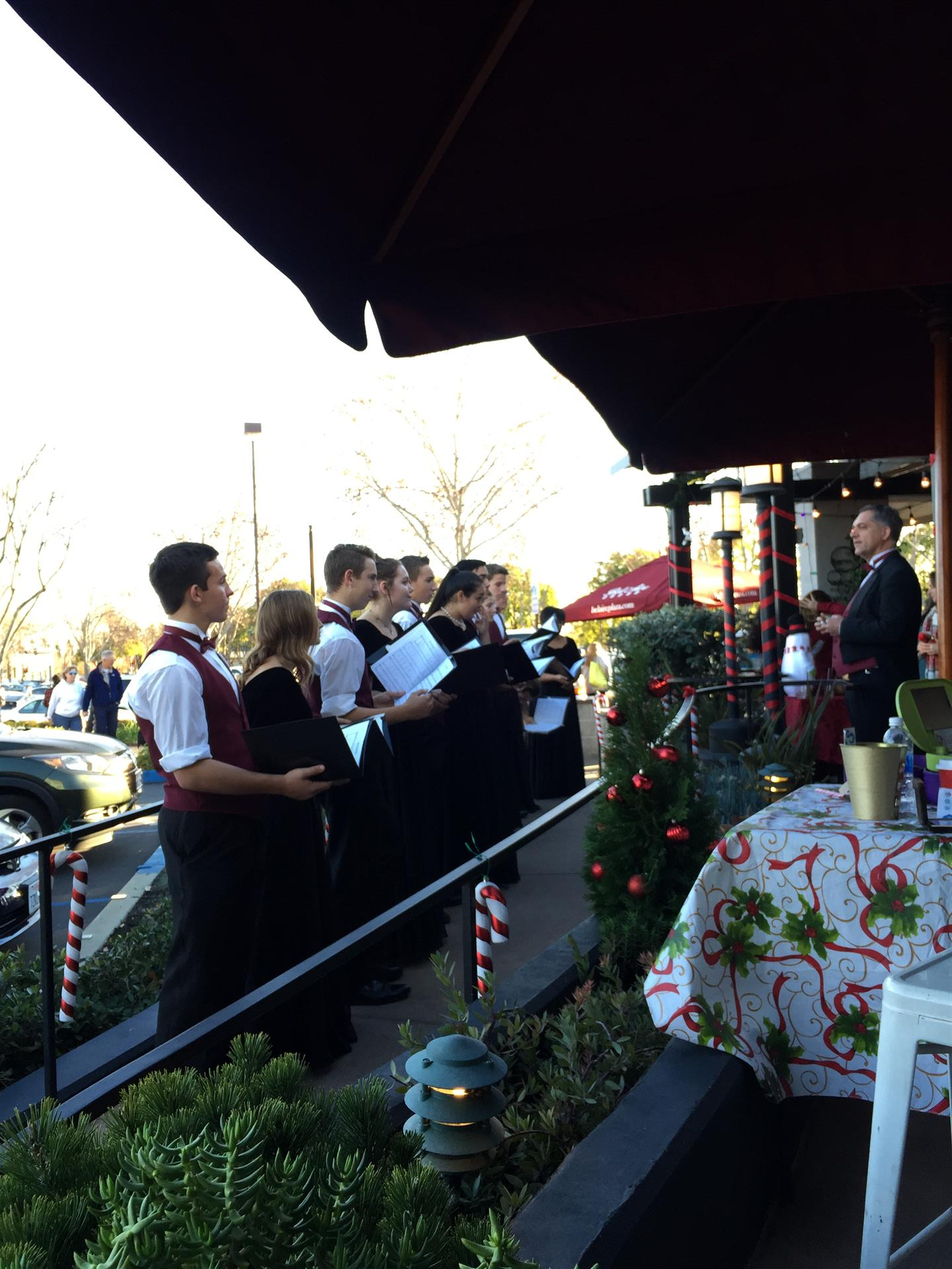 A group of people are singing outside of a restaurant