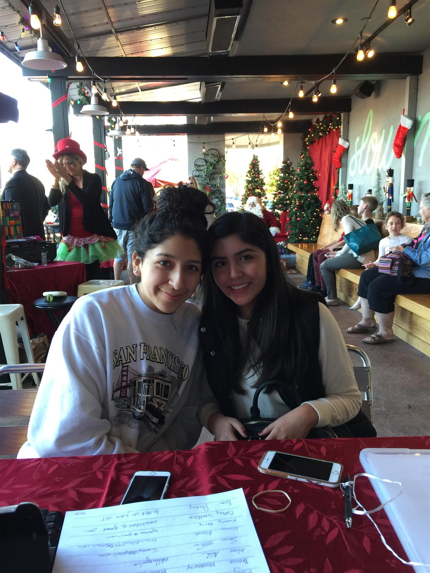Two girls are posing for a picture while sitting at a table in a restaurant.