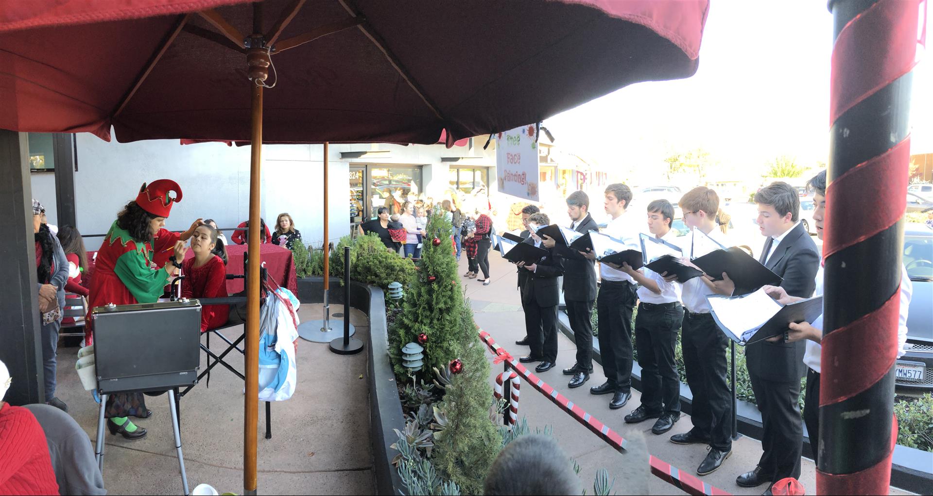 A group of people are singing under an umbrella.