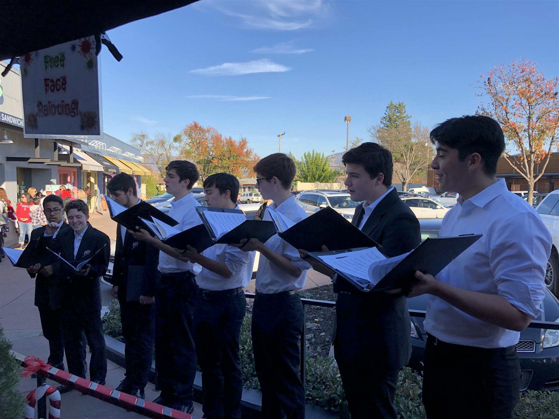 A group of young men are singing christmas carols in front of a building.