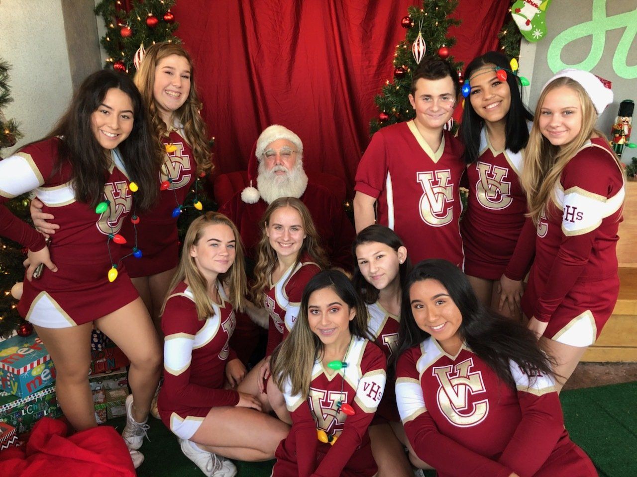 A group of cheerleaders are posing for a picture with santa claus.
