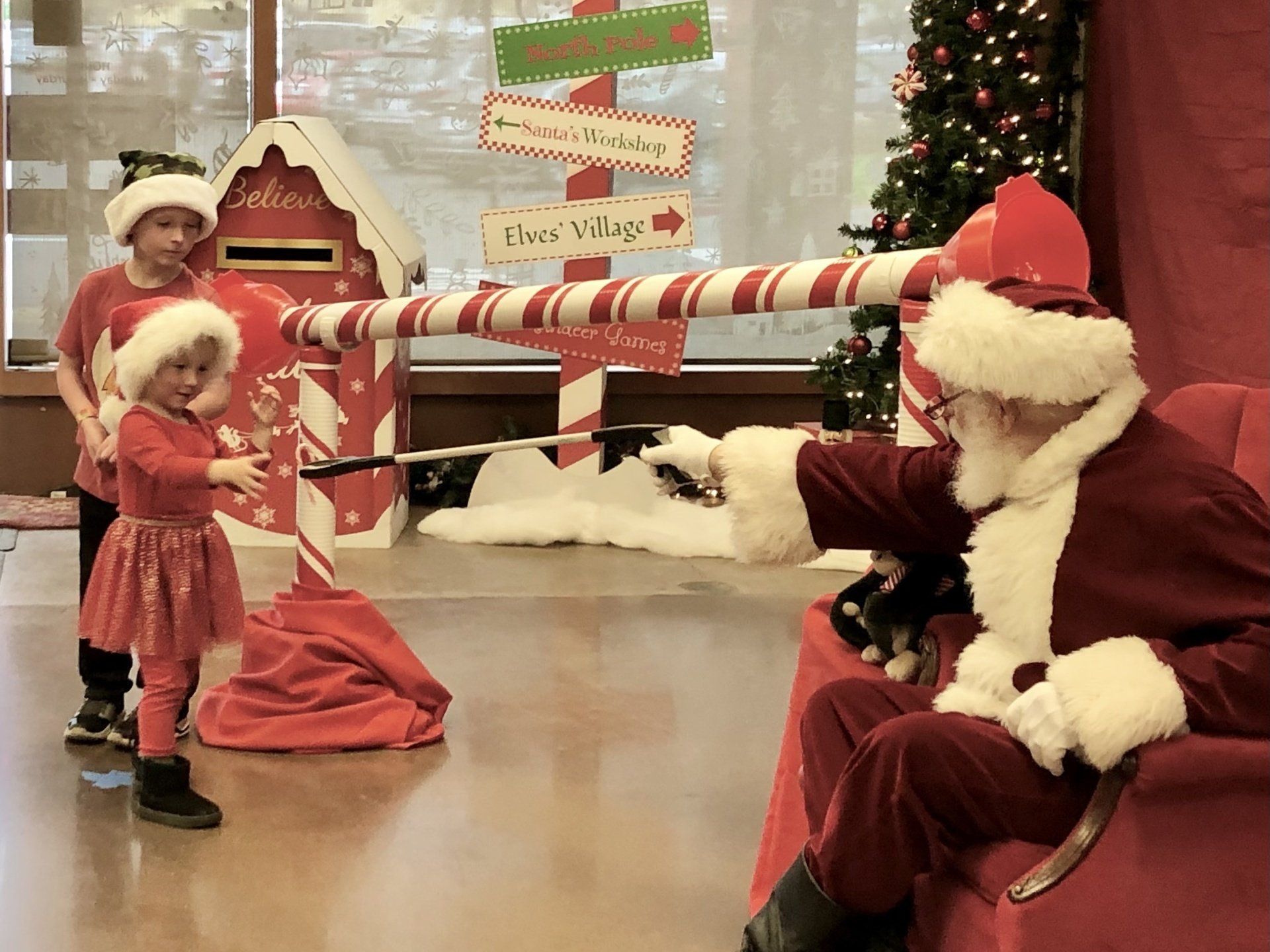 A little girl is holding a candy cane in front of santa claus