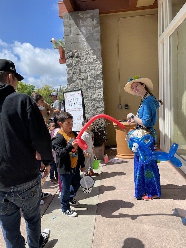 A woman is holding a balloon in the shape of a fish.