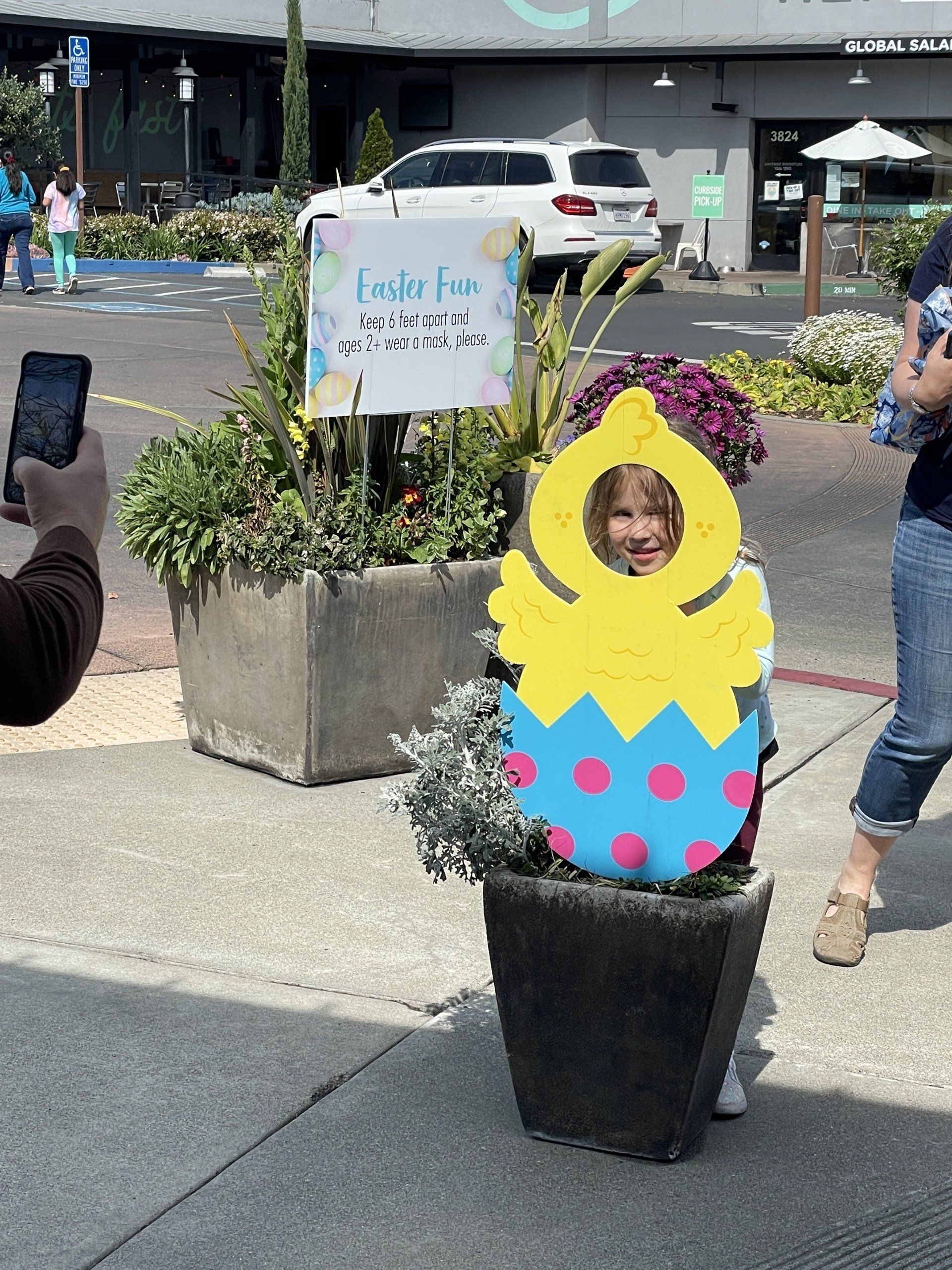 A person is taking a picture of a child dressed as an easter egg