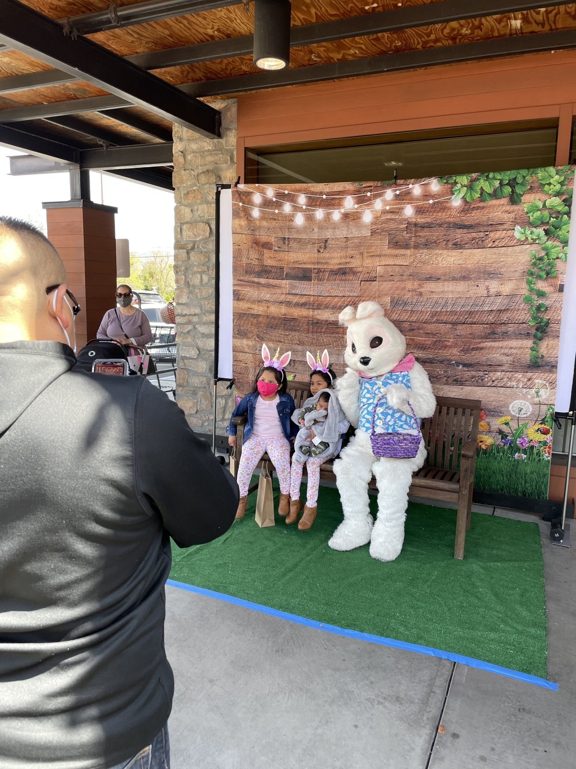 A man is taking a picture of two children and a bunny mascot.