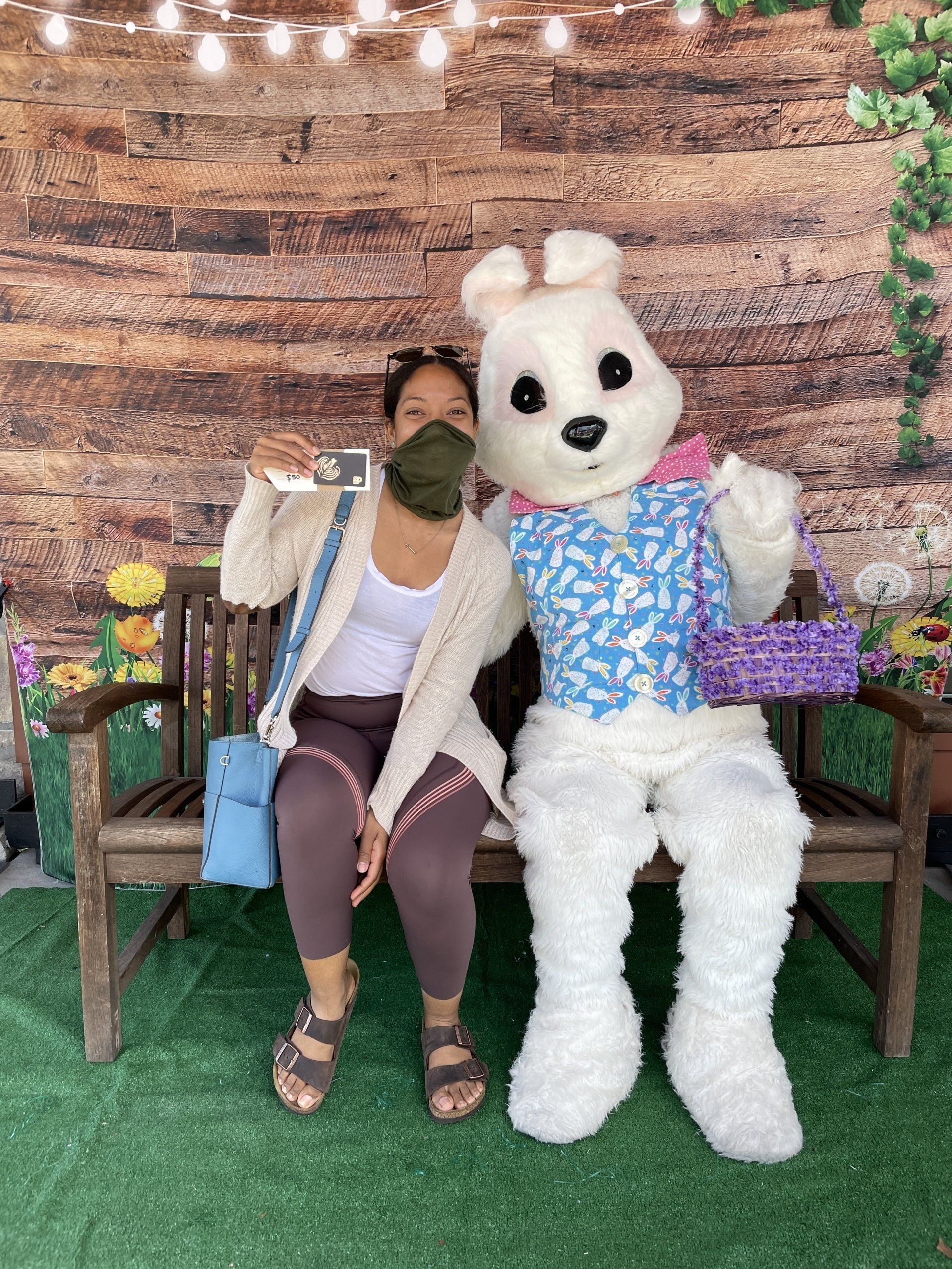 A woman is sitting on a bench next to a stuffed bunny.