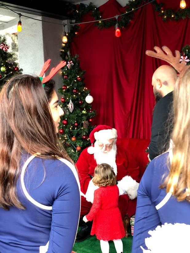 A little girl is standing in front of santa claus