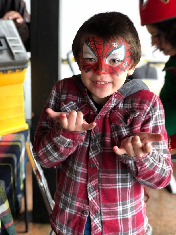 A young boy with his face painted like spider man