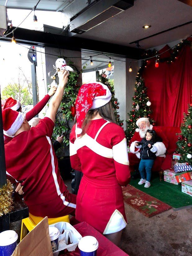 A woman in a santa hat is standing in front of a christmas tree
