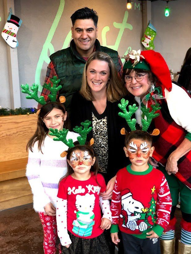 A group of people wearing christmas sweaters and reindeer antlers are posing for a picture.