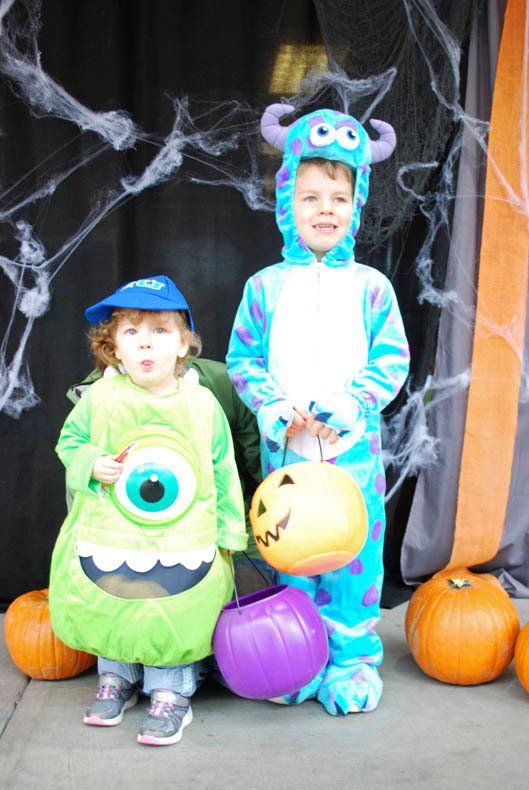 A boy and a girl in monsters inc costumes holding pumpkins