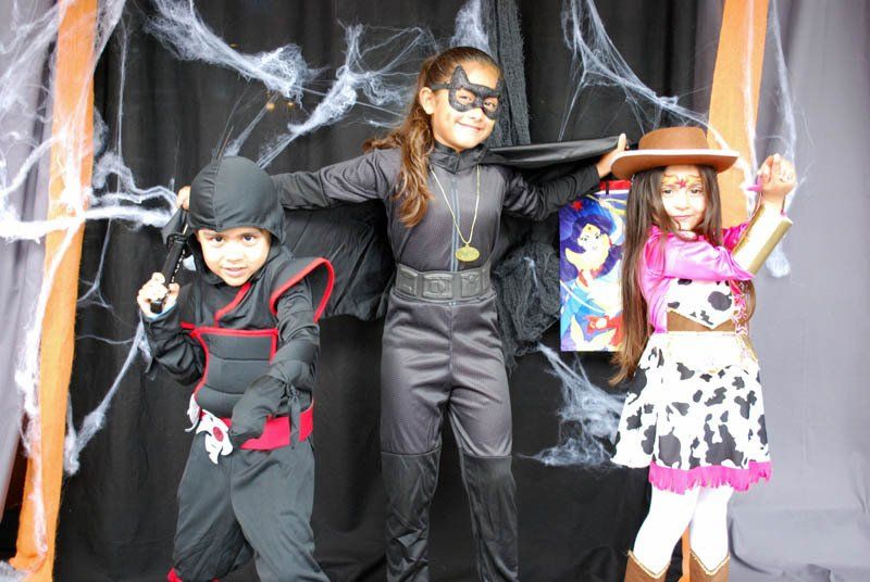 Three children in halloween costumes are posing for a picture.