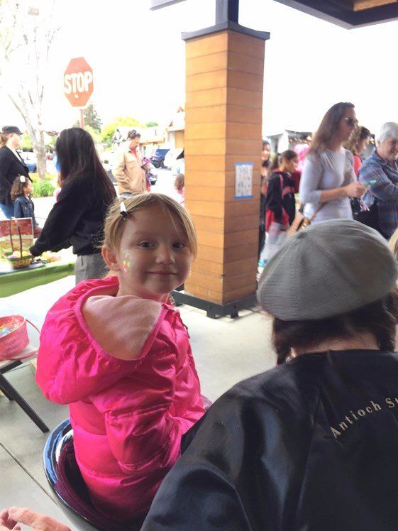 A little girl is sitting in front of a stop sign