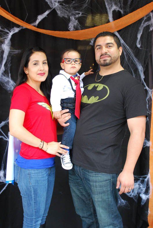 A man wearing a batman shirt is holding a baby