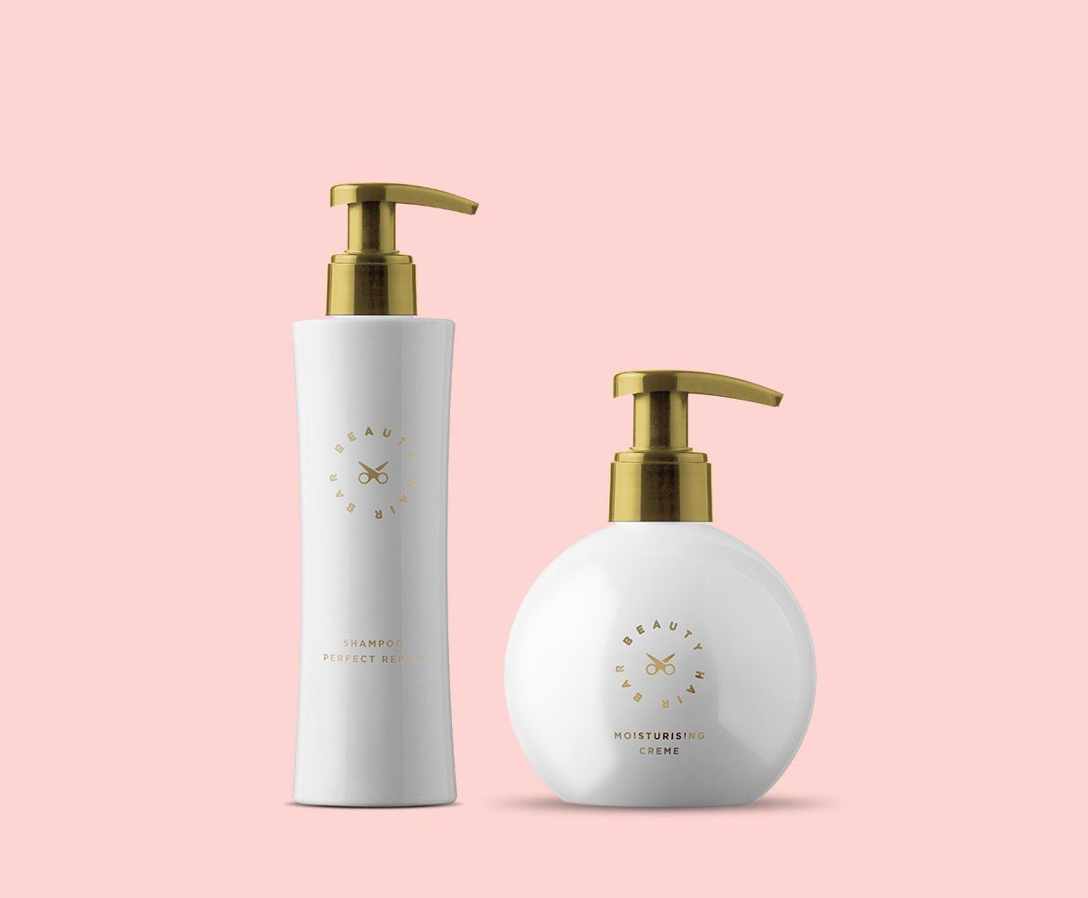 Two white bottles with gold pumps on a pink background.