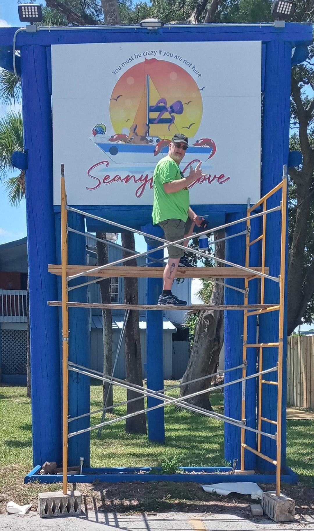 A man is standing on a scaffolding next to a sign.