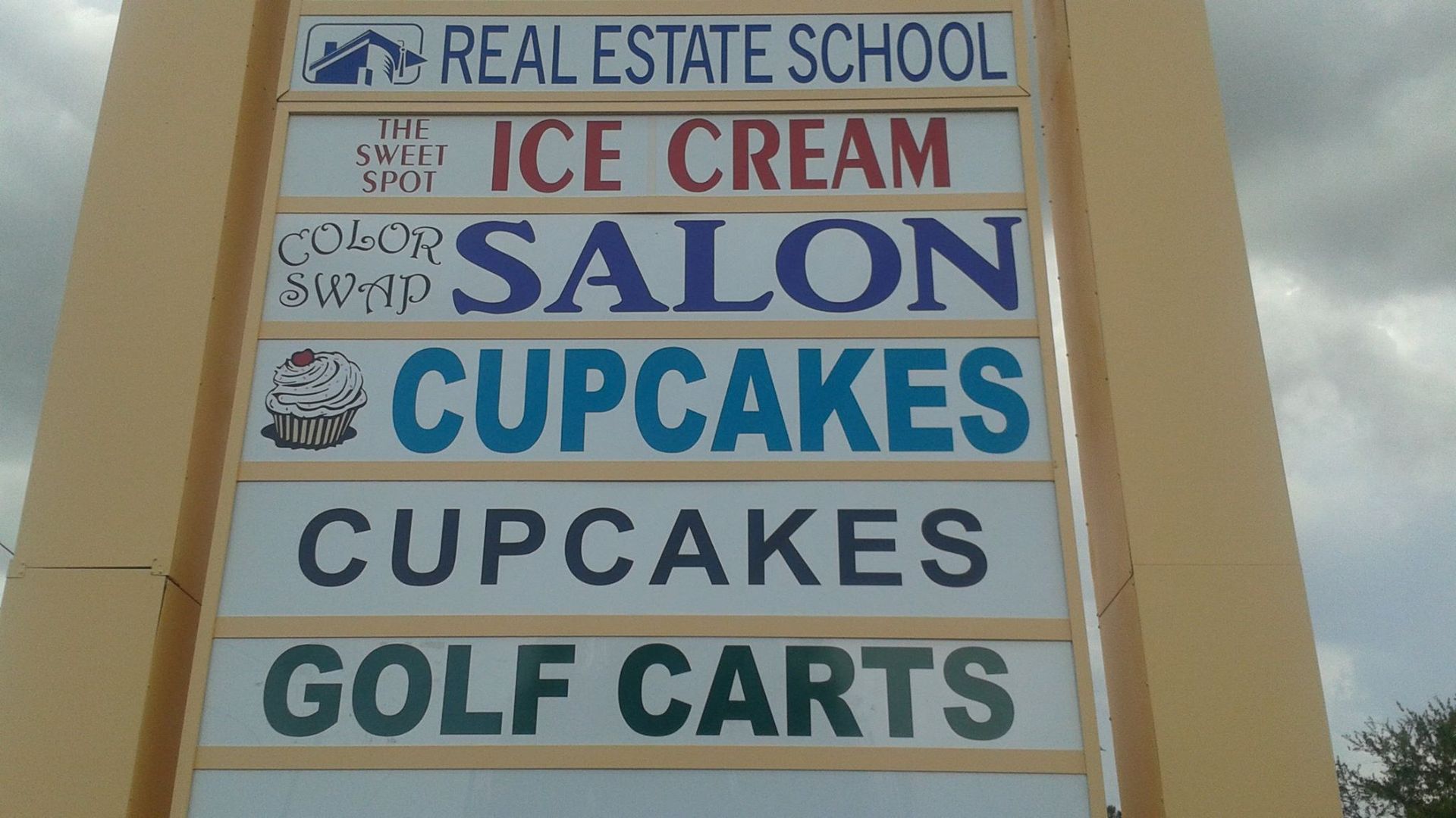 A sign that says real estate school ice cream salon cupcakes cupcakes golf carts