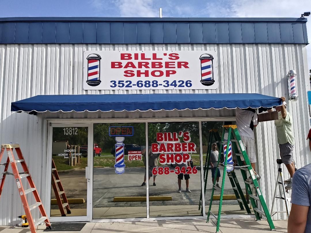 A barber shop is being remodeled with a blue awning.