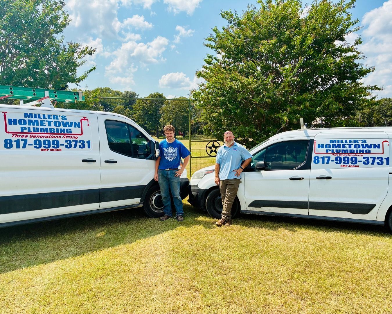 Two men stand by plumbing service vans on a grassy field; blue sky. The vans are white with business logos and phone numbers.