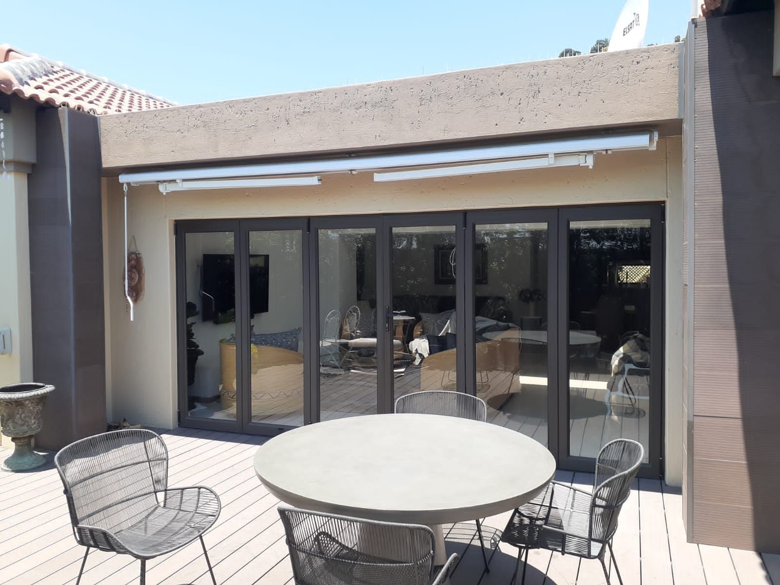 There is a table and chairs on the deck of a house.