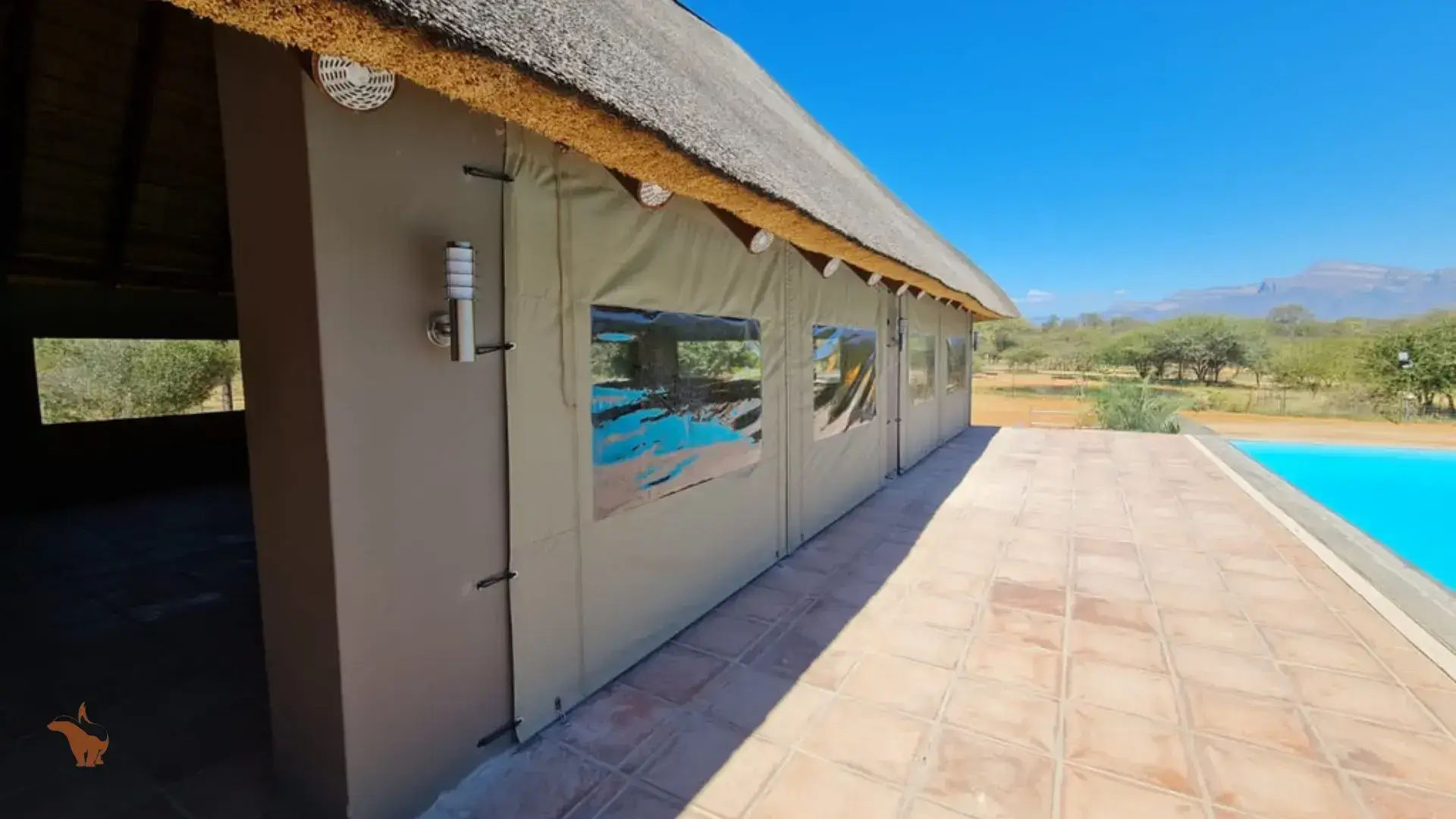 A building with a thatched roof and a swimming pool in the background.