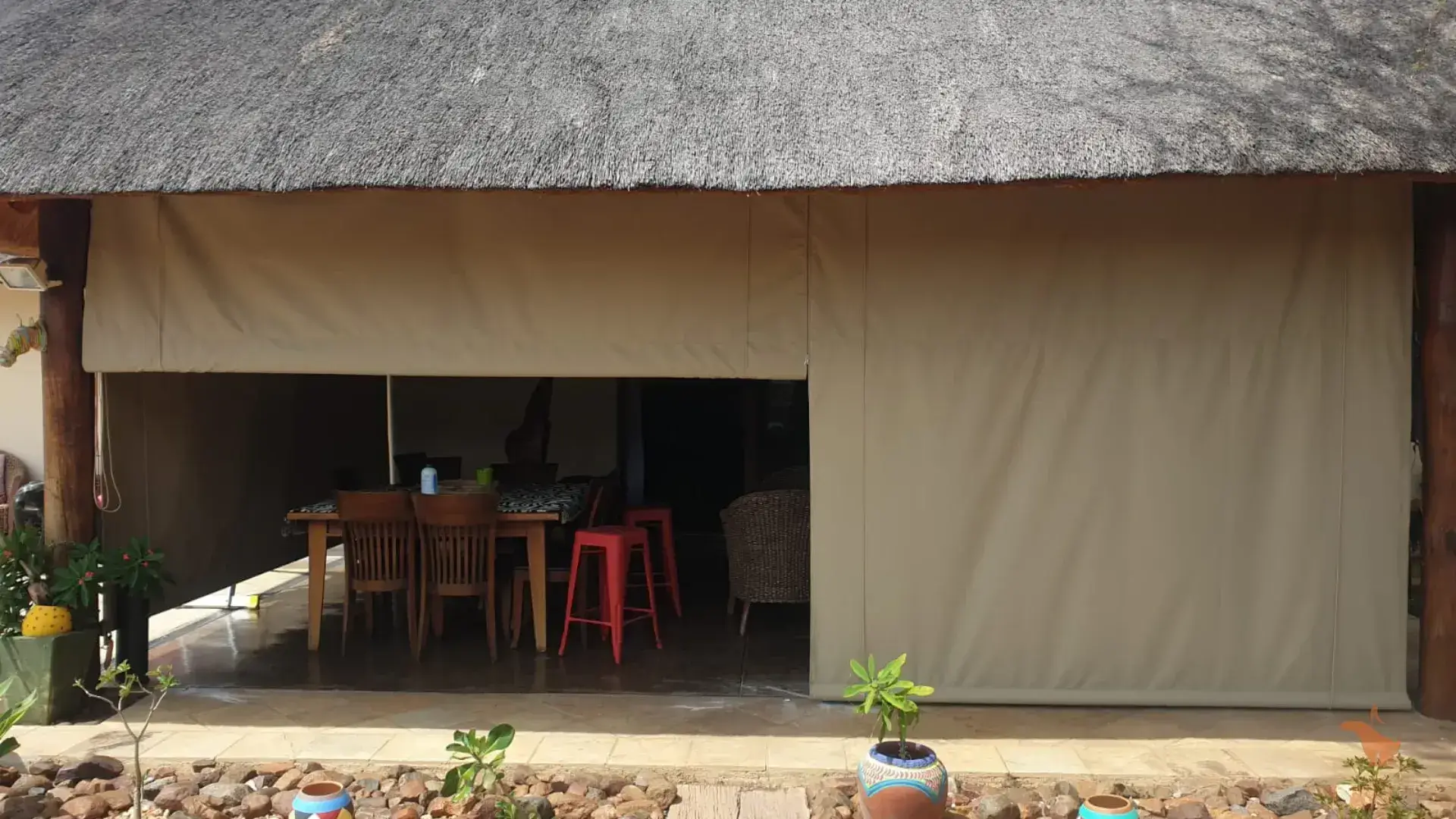 A thatched roof covered patio with a table and chairs.