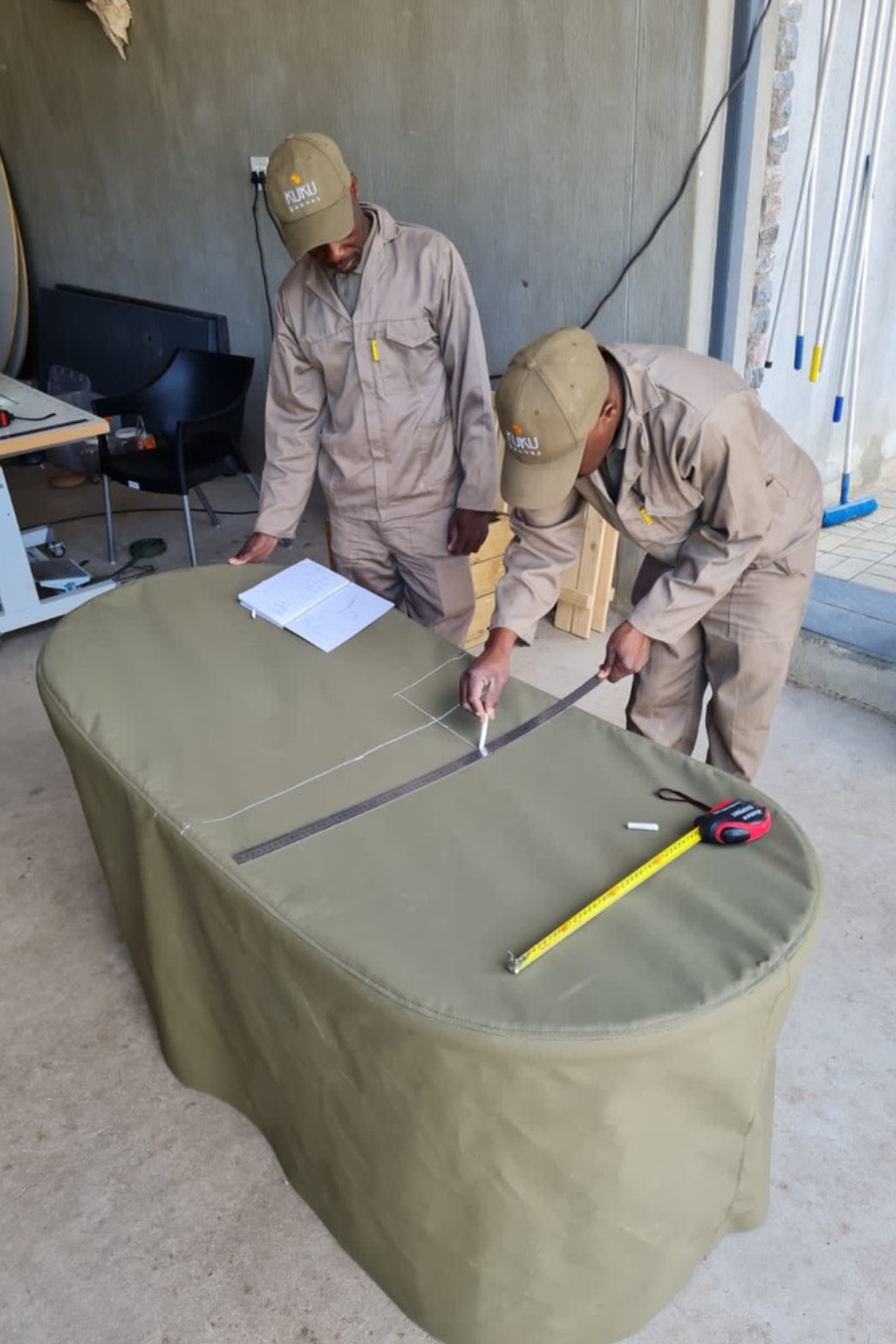 Two men are measuring a table with a tape measure.