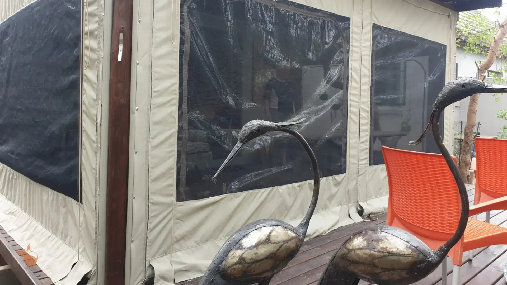 A statue of a bird is sitting on a wooden deck in front of a tent.