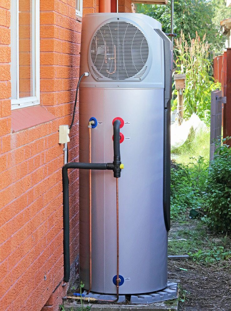 A Tall, Silver Heat Pump Water Heater Installed Outside a Brick Building — Mid Richmond Plumbers & Suppliers in Coraki, NSW