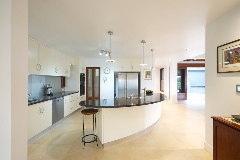 A Kitchen With White Cabinets and Black Counter Tops — Mid Richmond Plumbers & Suppliers in Coraki, NSW