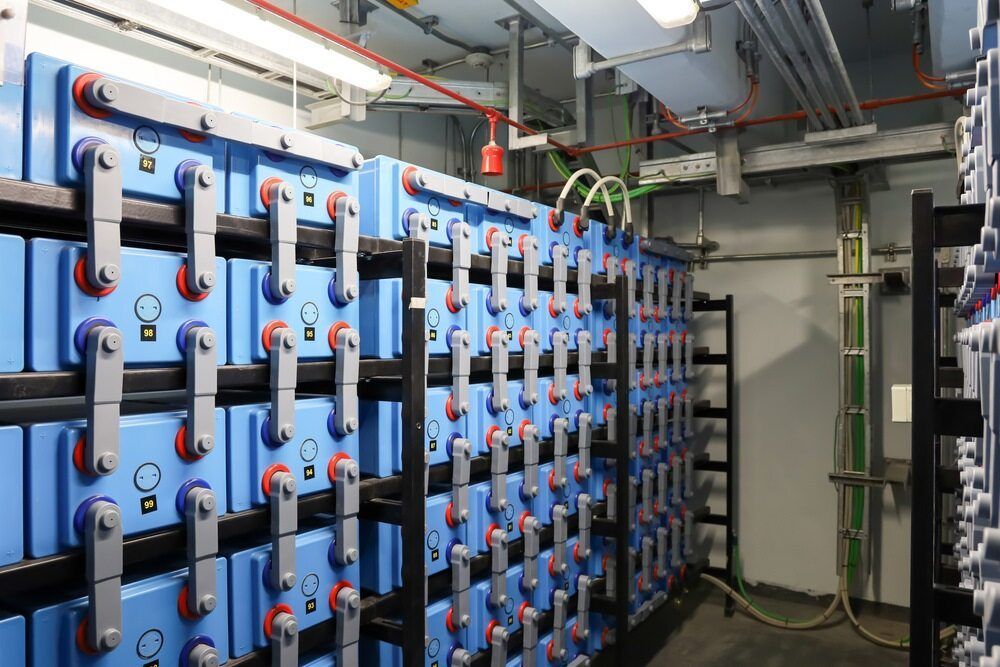 Rows of Blue Batteries Stacked on Black Metal Racks in a Room — Mid Richmond Plumbers & Suppliers in Coraki, NSW