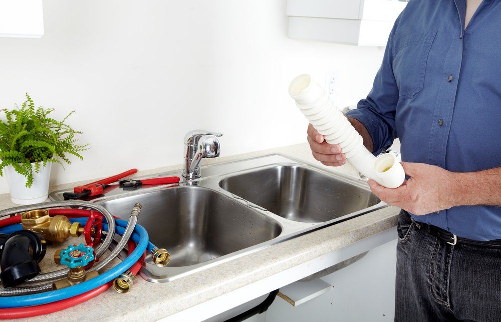 Man is Standing in Front of a Kitchen Sink Holding a Piece of Paper — Mid Richmond Plumbers & Suppliers in Mullumbimby, NSW