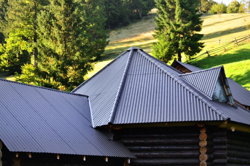 Log Cabin With a Corrugated Metal Roof is Sitting on Top of a Grassy Hill — Mid Richmond Plumbers & Suppliers in Coraki, NSW