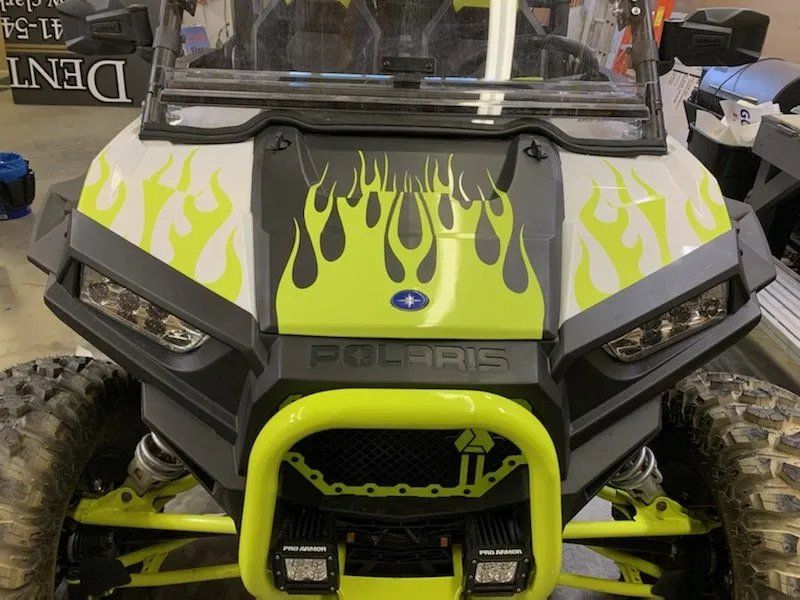 A yellow and black polaris atv with flames painted on it