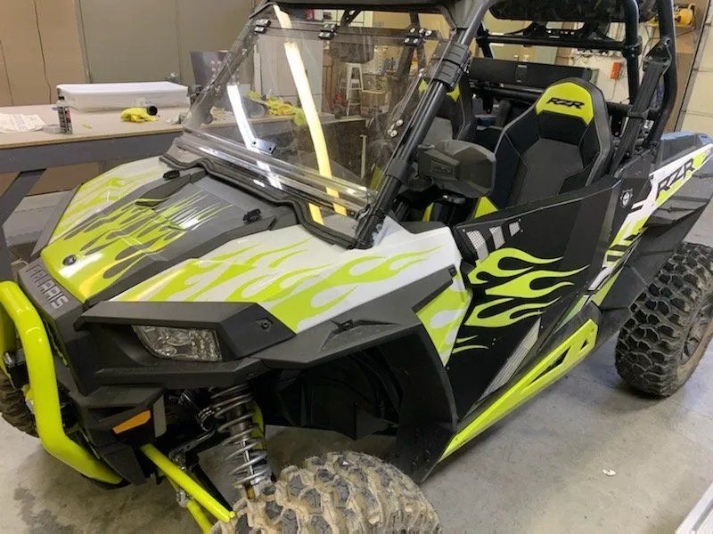 A yellow and black atv is parked in a garage.