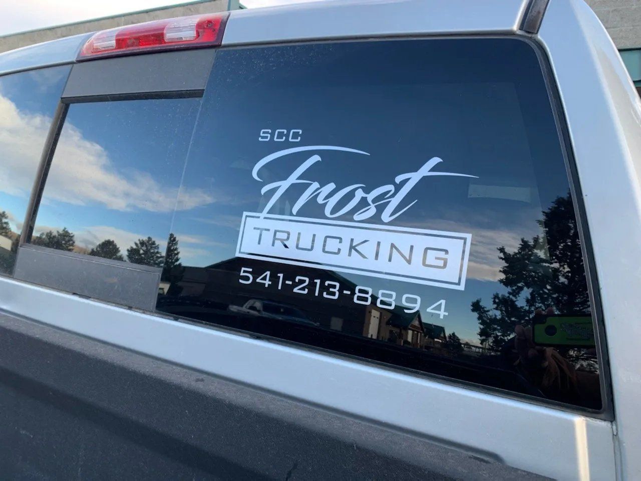 A truck with a sticker on the back window that says frost trucking.