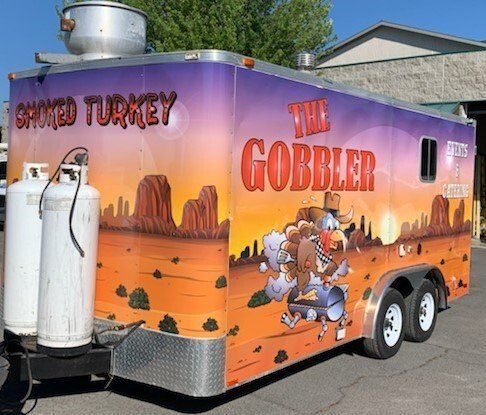 A trailer with a smoked turkey on it is parked in a parking lot.