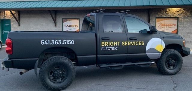 A black truck for bright services electric is parked in front of a building