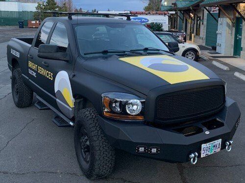 A black truck with a yellow stripe on the side is parked in a parking lot.